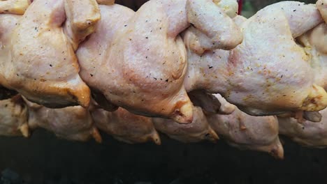 roasting trussed chickens on festival bbq rotisserie close-up slide shot