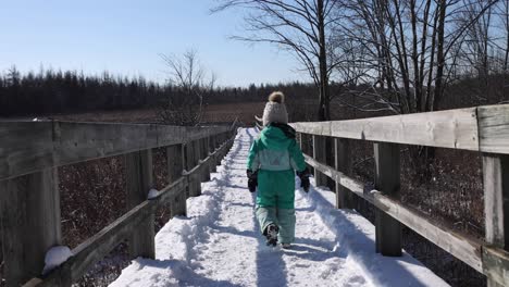 little girl walking down winter nature path slomo zoomed follow