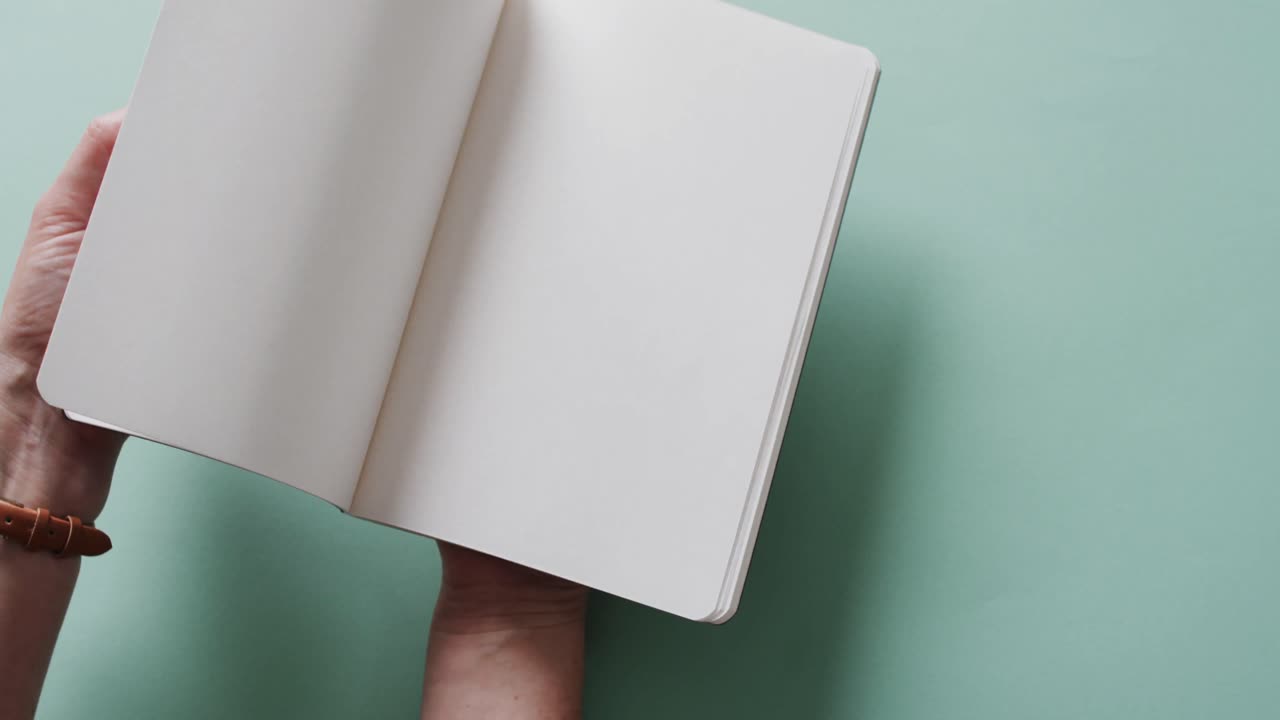 Close up of hand leafing through book with copy space on green background in slow motion