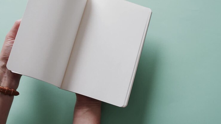Close up of hand leafing through book with copy space on green background in slow motion