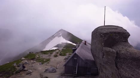 aerial shot of a shack on the top of a mountain ridge for climbers and hikers to rest for the night