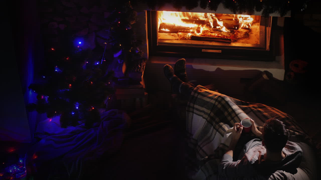 벽난로와 크리스마스 트리 옆에서 쉬고 있는 자신감 있는 젊은이