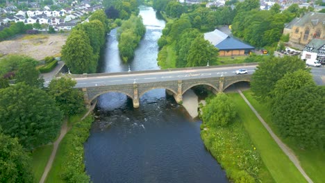 aerial drone shot flying northwest over the river tweed towards the tweed bridge in the town of peebles in the scottish borders