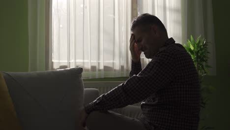 unhappy and depressed middle-aged man crying alone at home by the window.