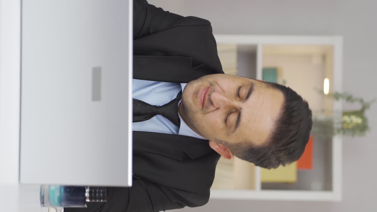 Vertical video of Home office worker man has fatigue.