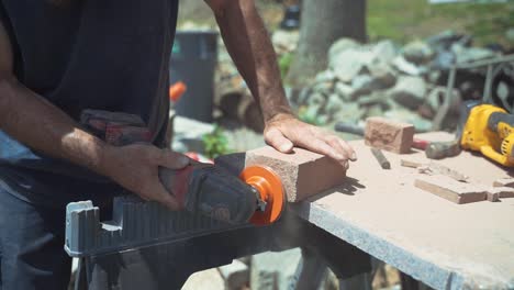 construction worker sawing and shaving bricks with electric power tools on sunny day, slow motion