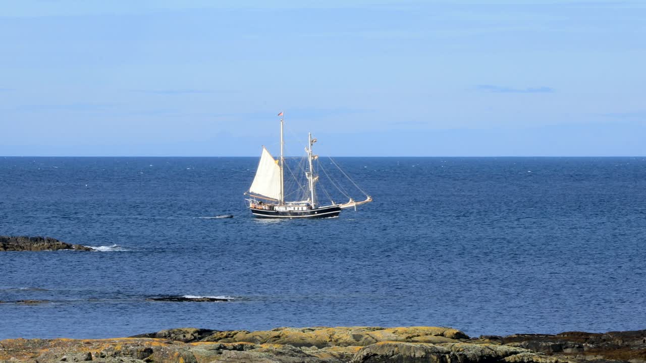 white sailing yacht on deep blue calm sea, west coast of scotland