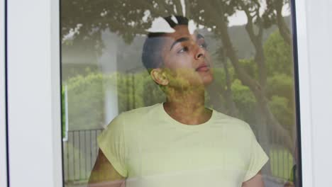 Portrait-of-mixed-race-man-standing-and-looking-out-of-window