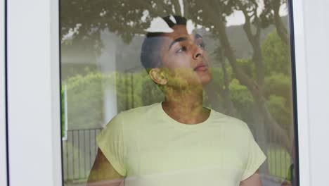 portrait of mixed race man standing and looking out of window