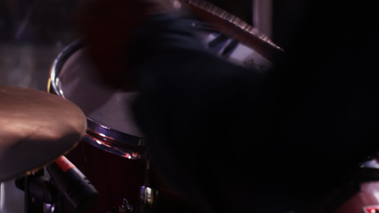 un hombre toca el tambor y los címbalos golpeando el instrumento musical con palos de tambor