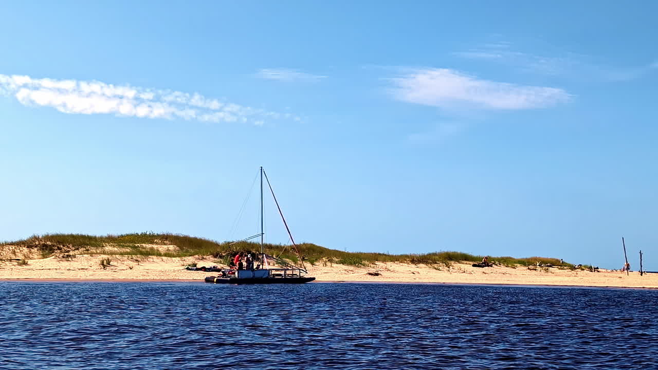 Pieni kalastusvene ankkuroituna joen rannalla kirkkaan sinisen taivaan alla Salacgrivassa, Latviassa.