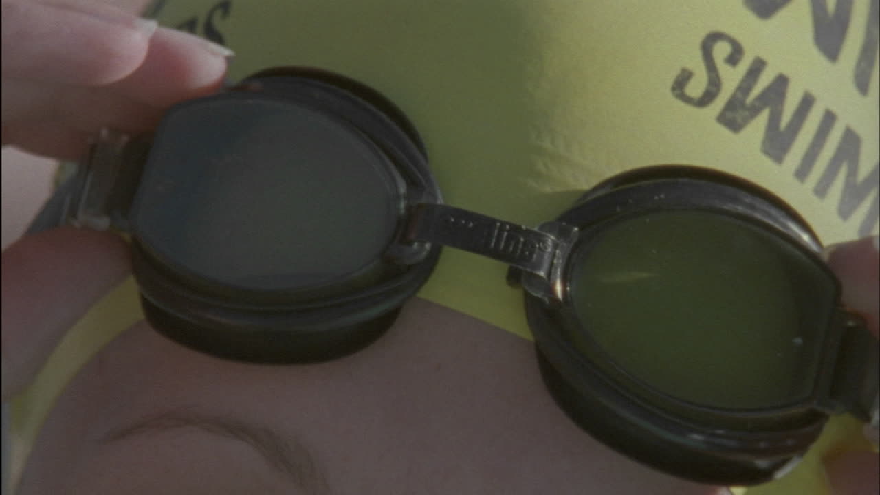 A swimmer adjusts her goggles and smiles