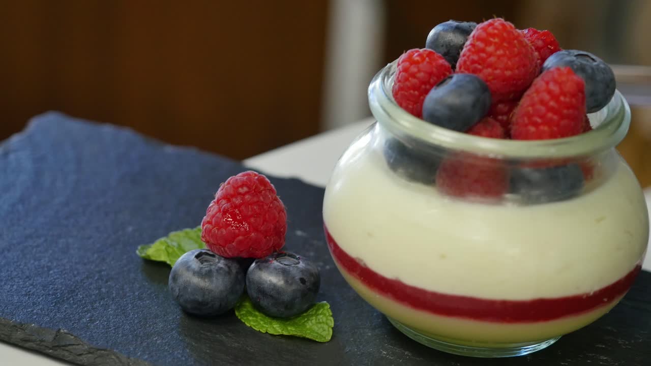 Preparing a layered dessert with raspberries and blueberries