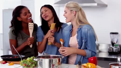 amigos riendo cantando en una cuchara de madera mientras cocinan
