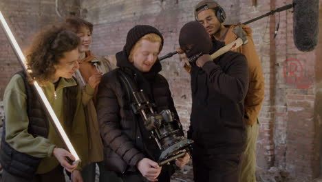 production team, cameraman and actors reviewing a scene movie in a camera and laughing in a ruined building