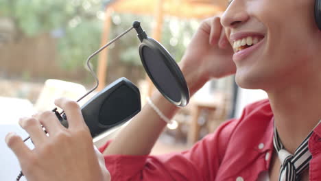 smiling teenage boy recording podcast using microphone and headphones at home