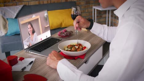 diverse couple on a valentines date video call woman on laptop screen smiling man eating meal