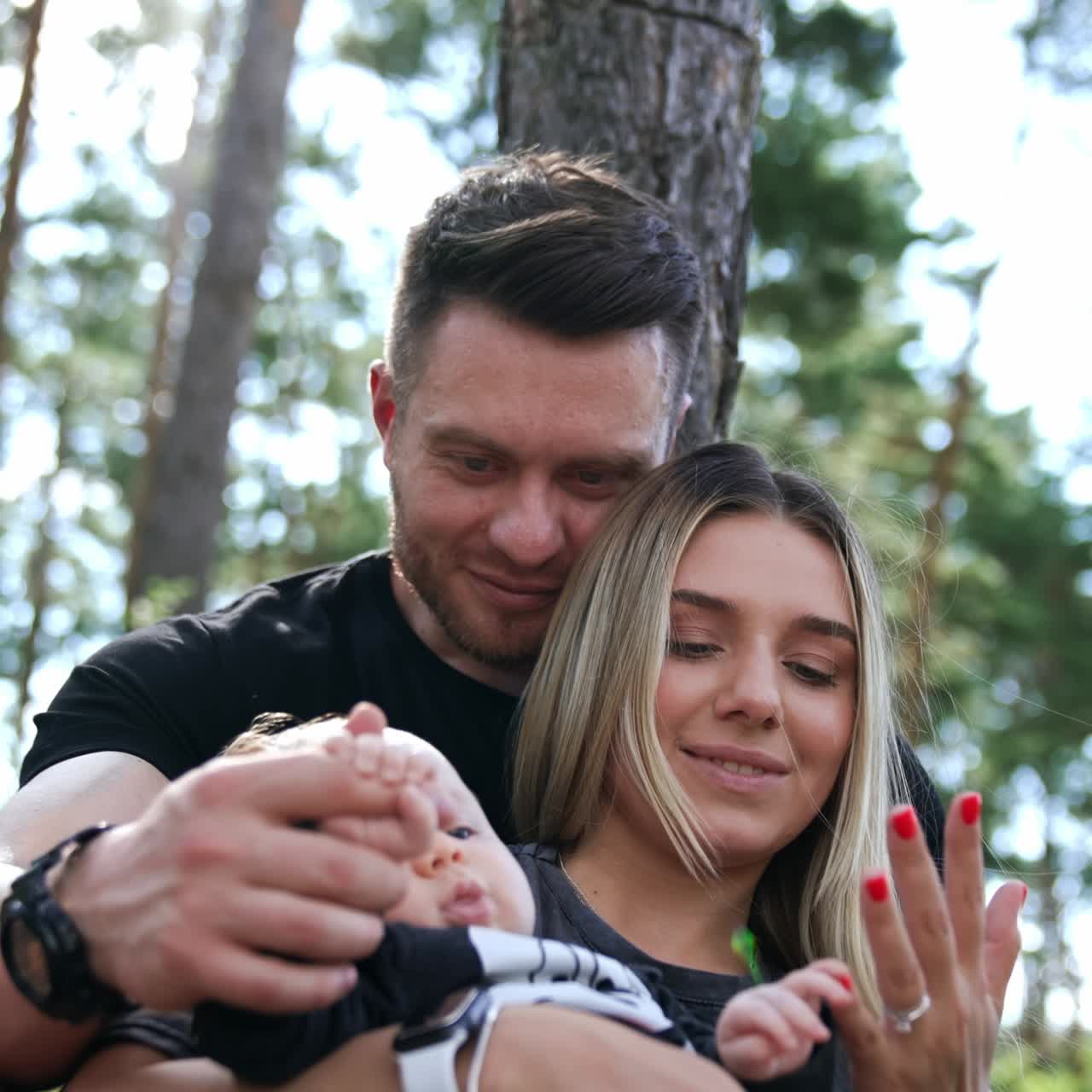 Beautiful Caucasian family of three. Happy people resting in nature with their newborn