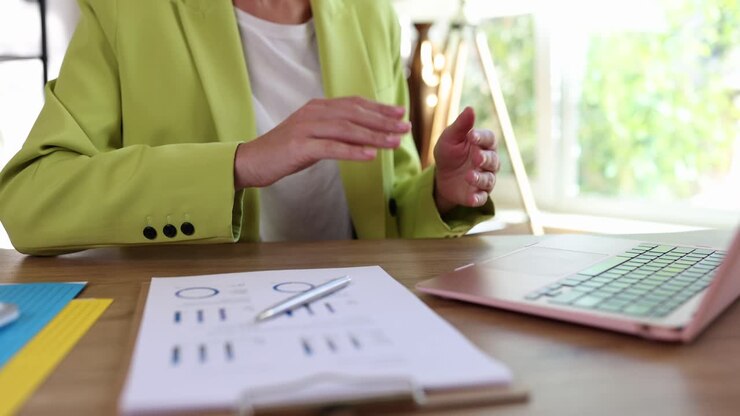 Businesswoman clapping at her desk with a laptop and chart
