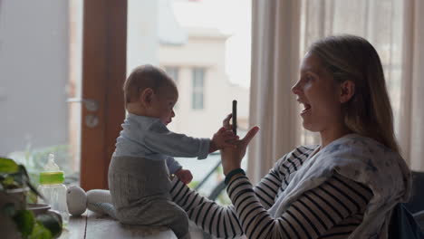 Madre-Feliz-Tomando-Una-Foto-Del-Bebé-Usando-Un-Teléfono-Inteligente-Disfrutando-Fotografiando-A-Un-Recién-Nacido-Compartiendo-El-Estilo-De-Vida-De-La-Maternidad-En-Las-Redes-Sociales