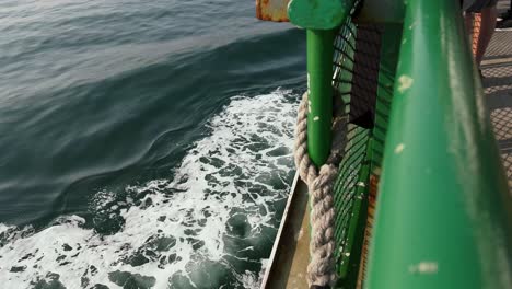 view of foamy wake on the water from port of a cruising ferry boat