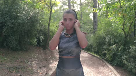 la chica se pone los auriculares en los oídos y comienza a correr en un parque