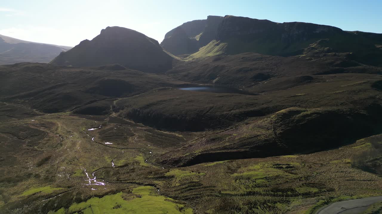 Vista in allontanamento di Loch Cleat e delle formazioni rocciose di Quiraing sulla cresta di Trotternish, Isola di Skye, Scozia