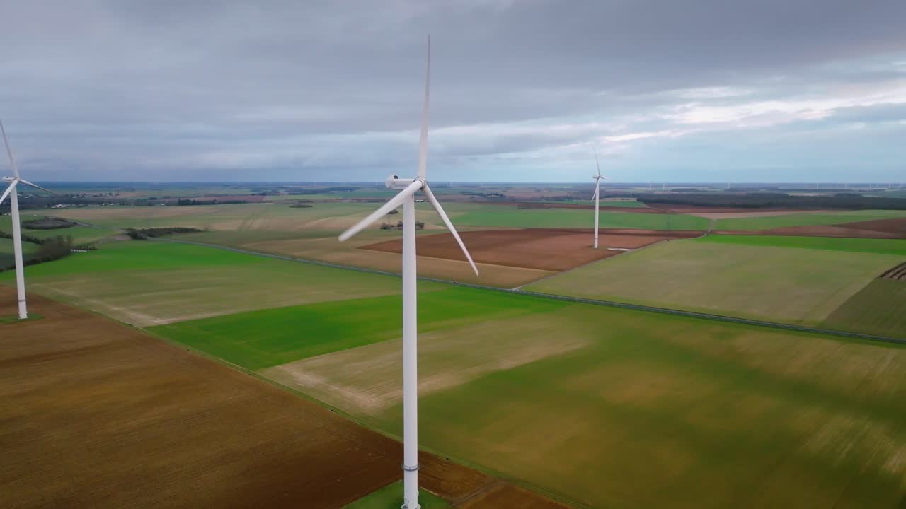 Beautiful new white wind turbines contrasting with the dark sky, advanced drone shot