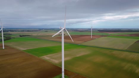 Schöne-Neue-Weiße-Windturbinen-Kontrastieren-Mit-Dem-Dunklen-Himmel,-Moderne-Drohnenaufnahme