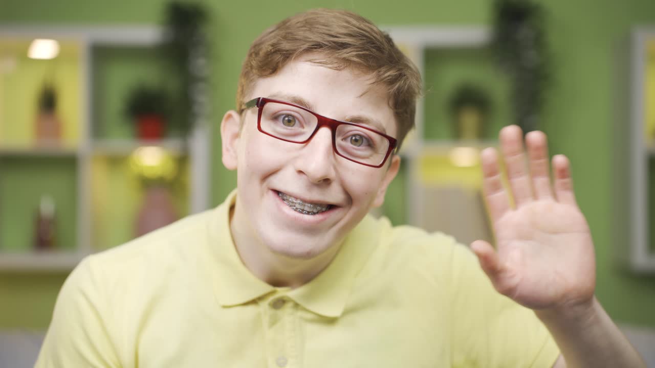 un joven divertido de primer plano saludando mientras mira a la cámara.