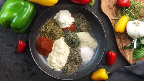 making a vibrant cajun spice blend, mixing red paprika, cayenne pepper, oregano, thyme, white garlic onion powder and black pepper in a bowl, creating a striking contrast against a black background.