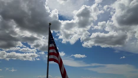 american flag usa blowing waving in the wind on beautiful sunny summer day with clouds and blue skies overlooking mountains in 4k 60fps