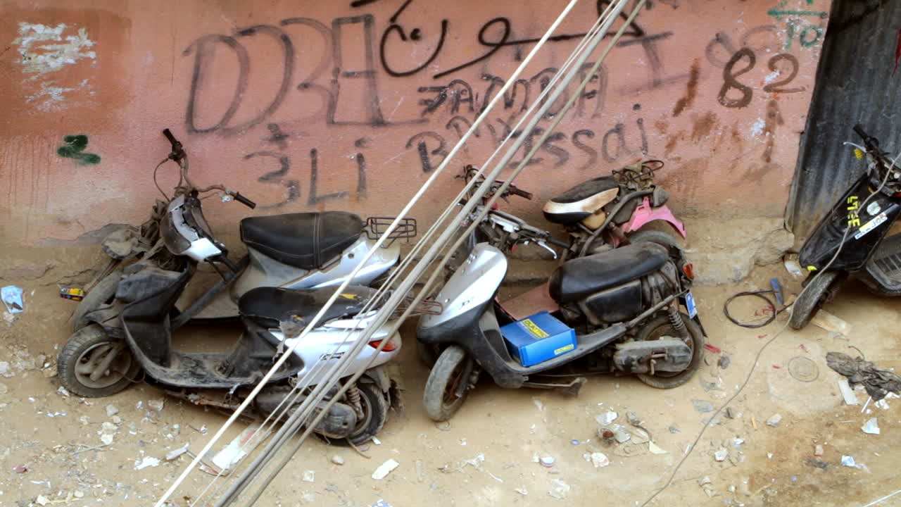 Scooters Amidst Trash and Bullet-Ridden Buildings in Palestinian Camp, Lebanon