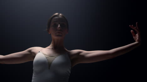 una tierna bailarina mirando a la cámara en un fondo oscuro. bailarina de ballet clase de baile