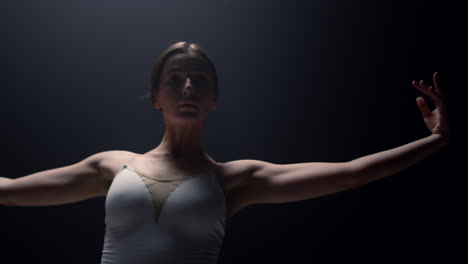 tender ballerina looking camera in dark background. ballet dancer dancing class