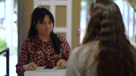 ethnic woman talking to colleague in lobby