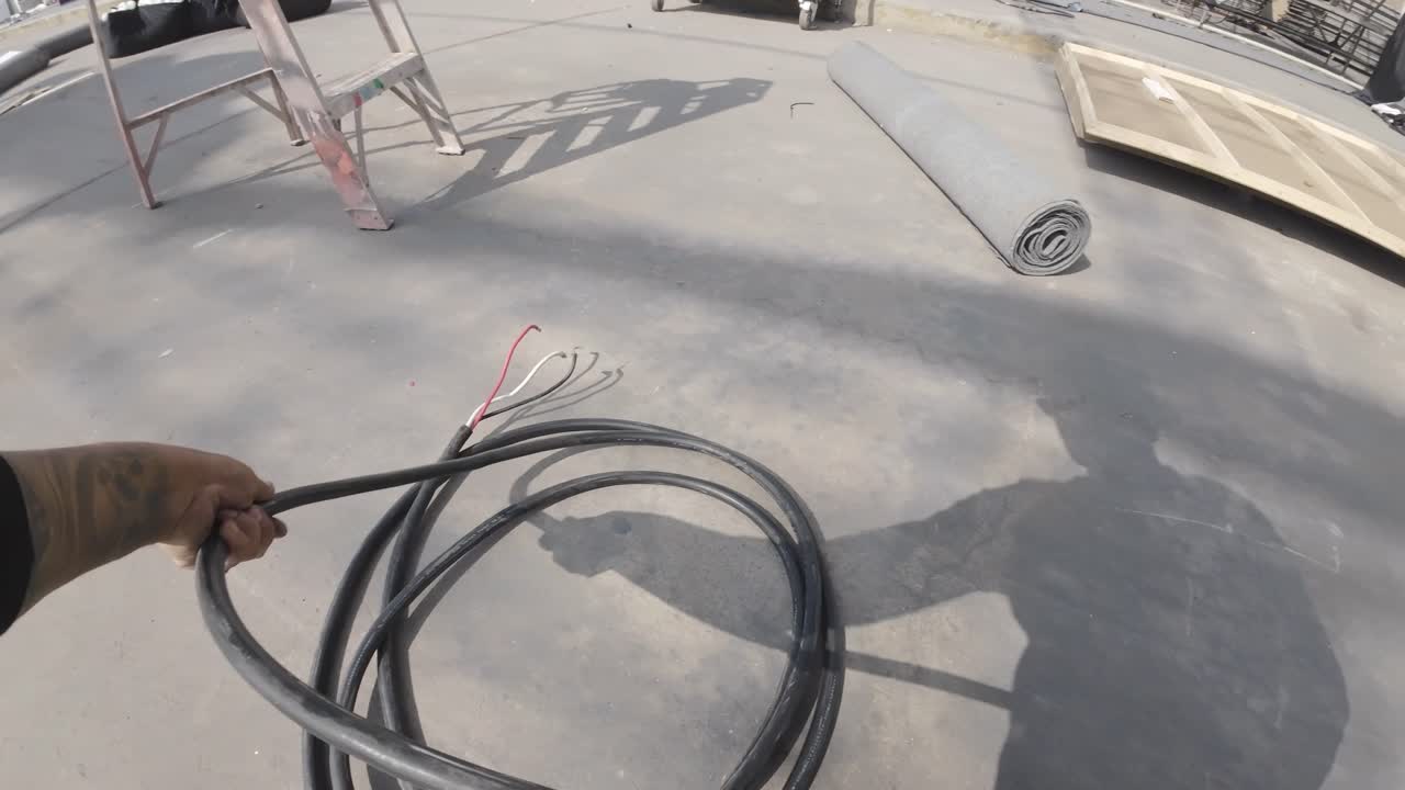 Førstepersonsperspektiv af arbejder, der ruller kabel sammen på en byggeplads