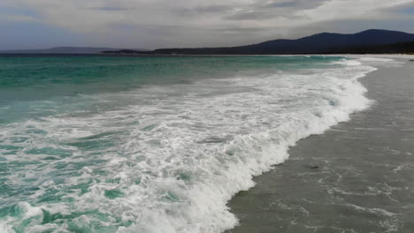 Aerial-view-of-waves-at-a-beach,-cloudy-day-in-Australia---reverse,-drone-shot