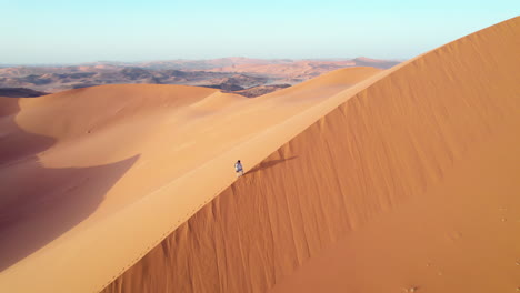 man in the sand dunes of the algerian sahara desert, djanet, algeria - aerial drone shot