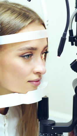 young woman checking her eyes in clinic. biomicroscopy device. doctor examining eye structure of a female patient with the help of modern medical equipment. professional health care. vertical video