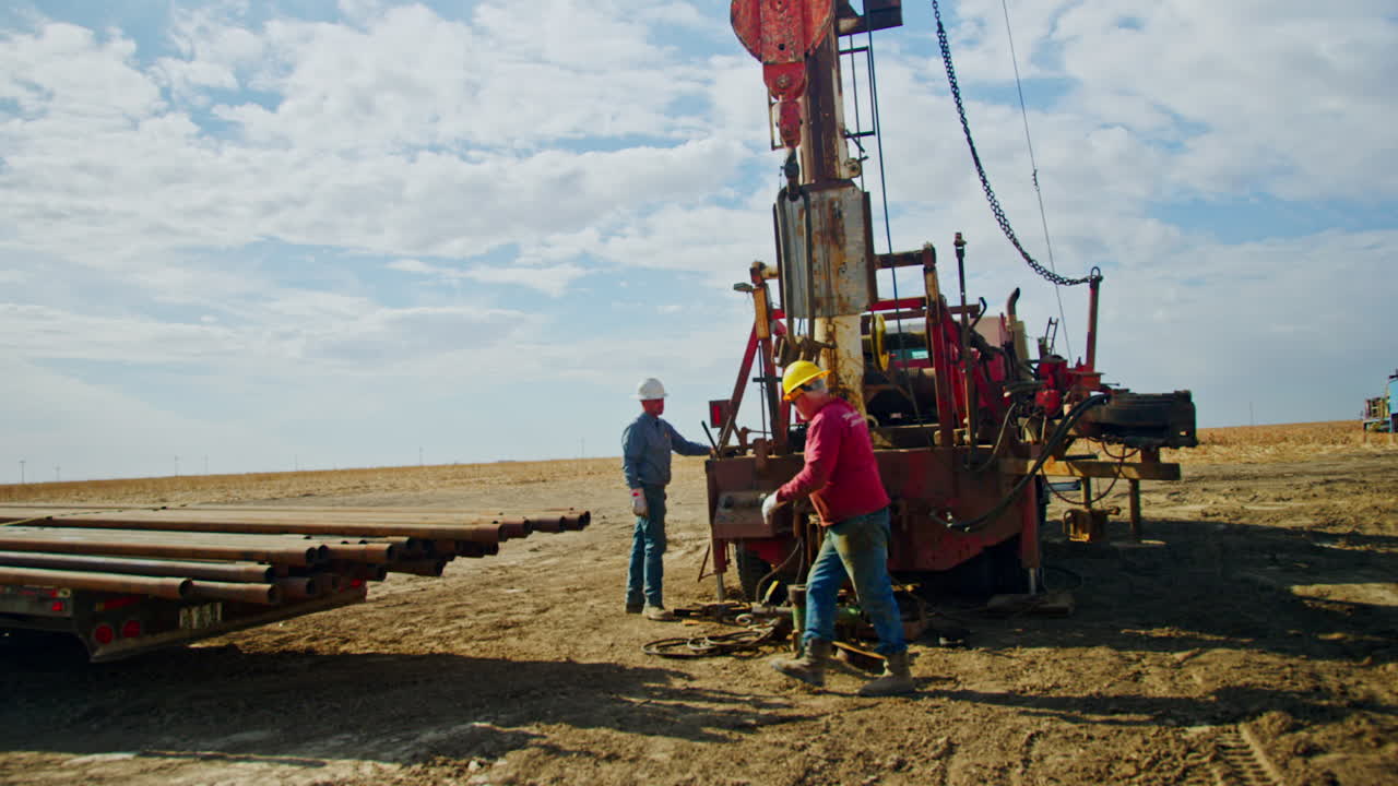 Male workers stand at the truck with the crane. Men are setting the equipment for oil and gas drilling.