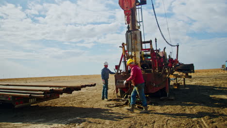 male workers stand at the truck with the crane. men are setting the equipment for oil and gas drilling.