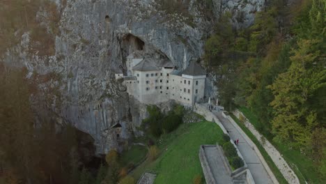 disparo aéreo de ángulo alto en cámara lenta en el castillo de predjama al atardecer