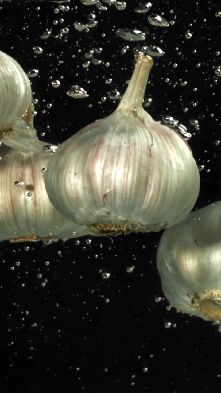 Bulbi d'aglio che galleggiano nell'acqua con bolle che salgono