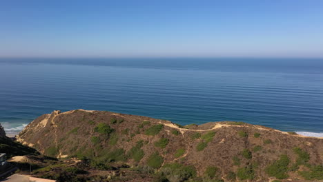 panoramic view above torrey pines and luxurious la jolla real estate with revealing shot of scripps pier in distance - panning drone