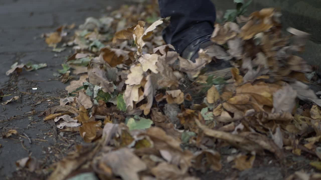 piernas pateando hojas de otoño en un camino plano medio