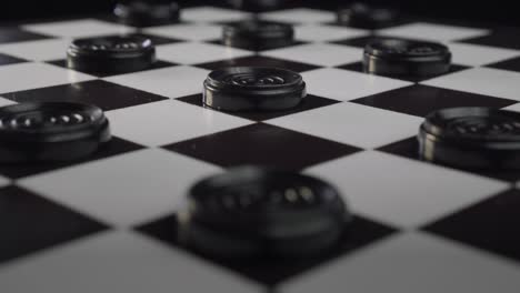 checkers board with black pieces lit up by shafts of light (draughts)