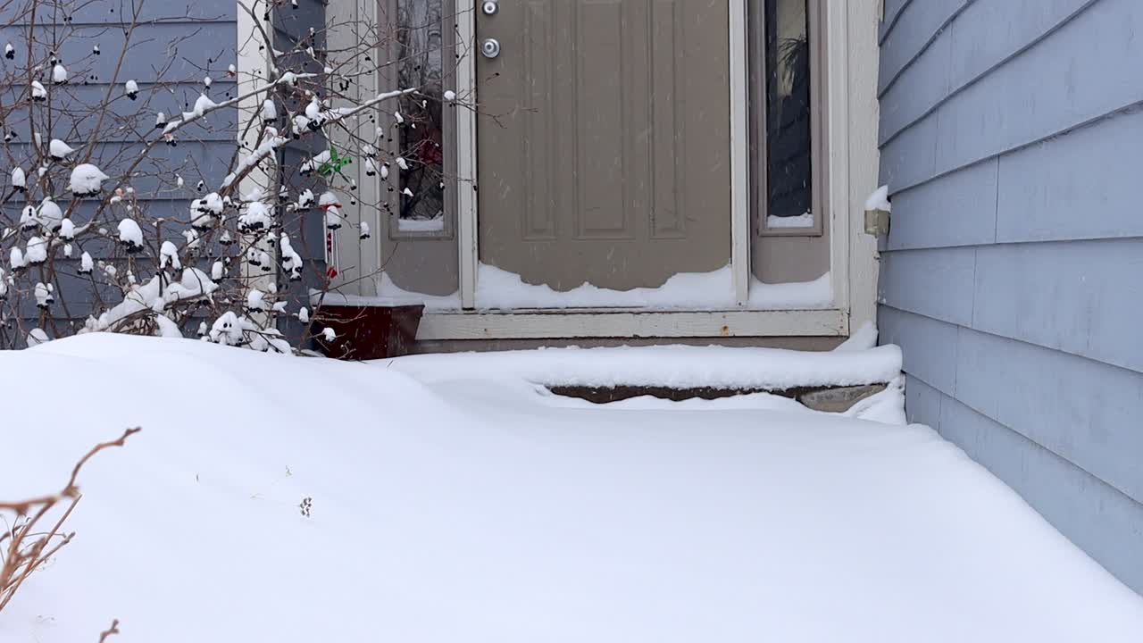 frío y nieve invernal cayendo en el porche de una casa suburbana
