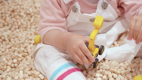 cropped portrait of a female toddler playing mini tractor toy