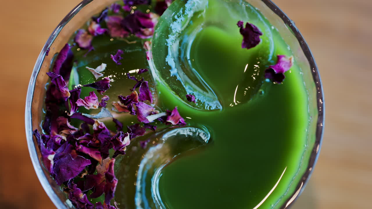 Primer plano de un té matcha con hielo en un vaso con flores moradas secas encima